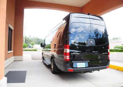 A black funeral limousine parked in front of a building