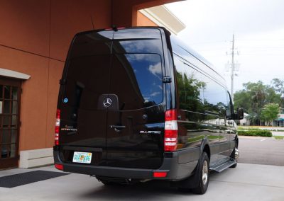 A black funeral limousine parked in front of a building